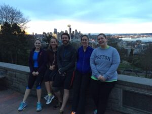 "Five sunrise climbers, wearing workout clothes with the Seattle skyline behind them."