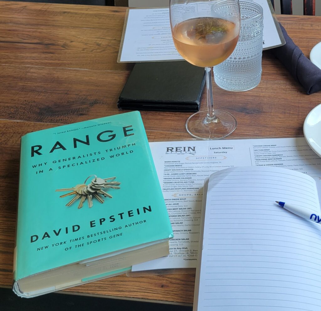 Range book with open notebook and pen and a glass of rosé.